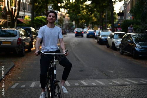 Smiling Dutch student riding home on his bicycle after a long day of studying at the university