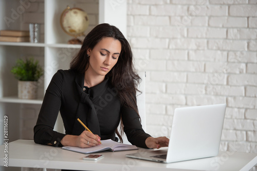 Beautiful stylish business lady working in a white office at a laptop. Women's business and modern technology