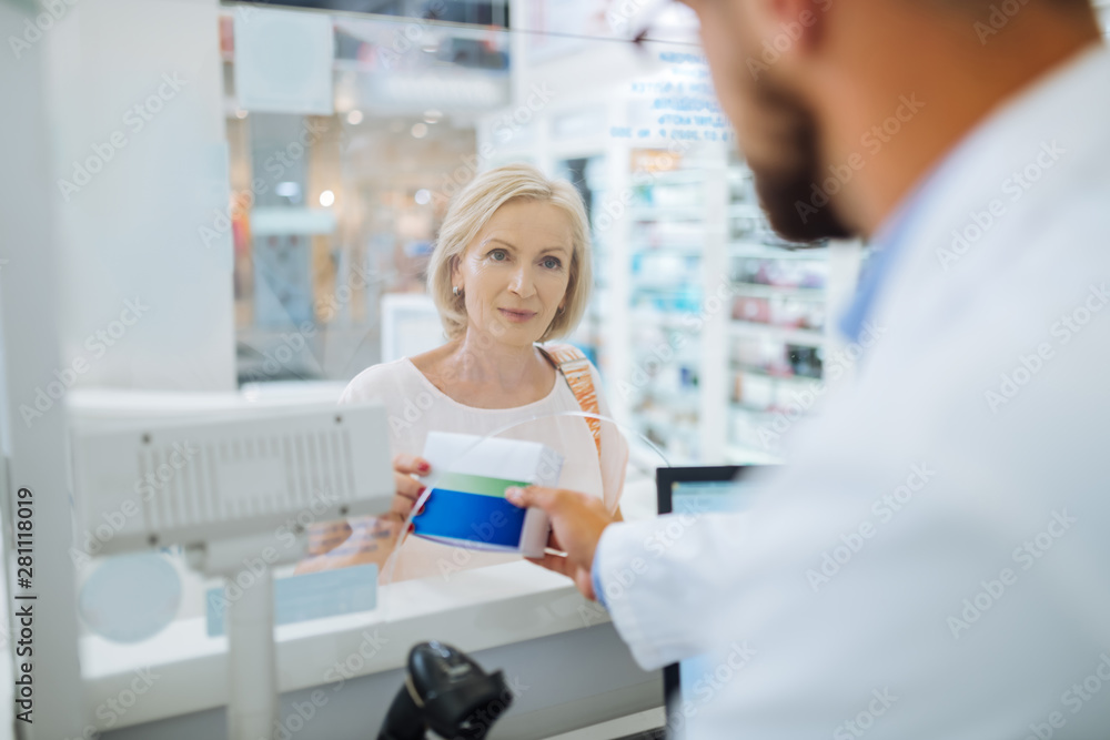 Charming mature female person buying necessary medicine Charming mature female person buying necessary medicine