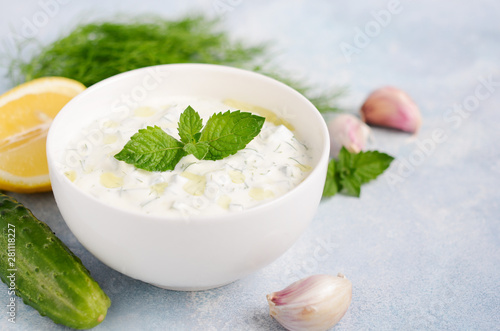 Greek dip sauce or dressing tzatziki decorated with olive oil and mint on blue background