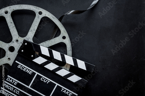 Movie premiere concept with clapperboard, film type on black background top view space for text