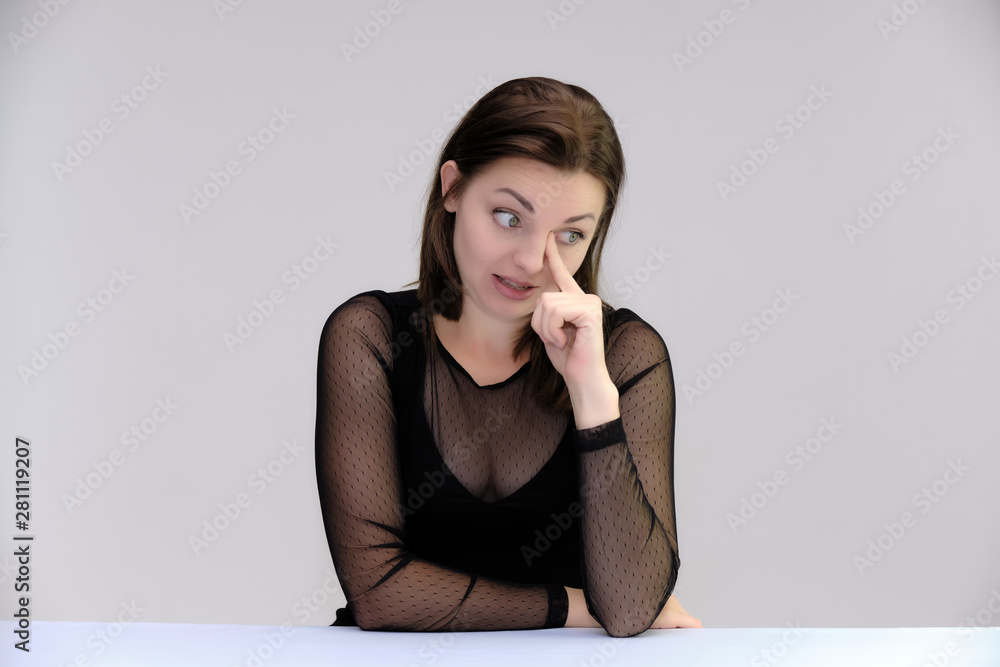 Portrait of a pretty beautiful fashionable adult girl with beautiful brunette hair in a black dress. Sits at the table directly in front of camera, talking demonstrating different poses and emotions Portrait of a pretty beautiful fashionable adult girl with beautiful brunette hair in a black dress. Sits at the table directly in front of camera, talking demonstrating different poses and emotions