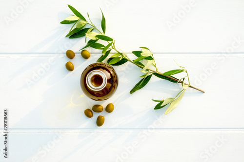bottle of olive oil with olives and and an olive branch
