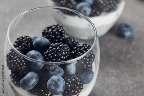 selective focus of tasty yogurt with chia seeds, blueberries and blackberries in glasses