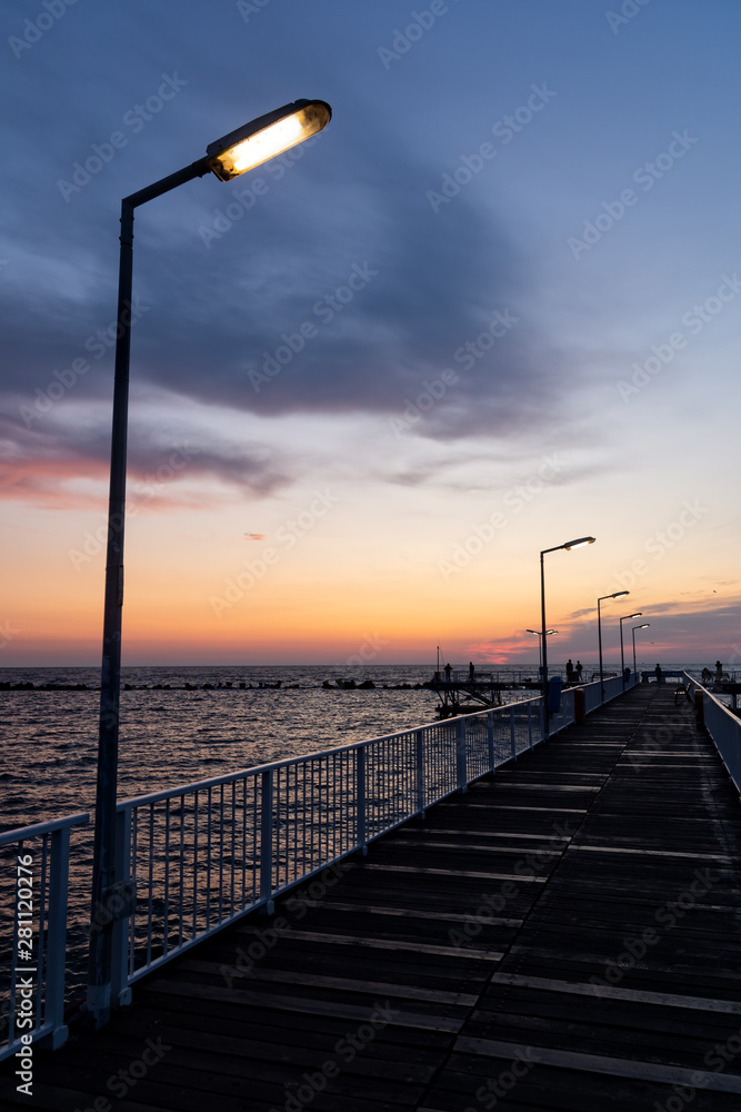 Portrait picture of a walkway with light poles over Black Sea in Constanta, Romania. Golden sunrise over sea