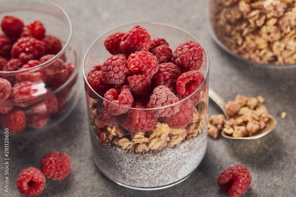 selective focus of tasty yogurt with raspberries, oat flakes and chia seeds near teaspoon on marble surface selective focus of tasty yogurt with raspberries, oat flakes and chia seeds near teaspoon on marble surface