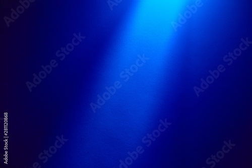On a blue finely textured semi-blurred background a light blue vertiacl ray of light