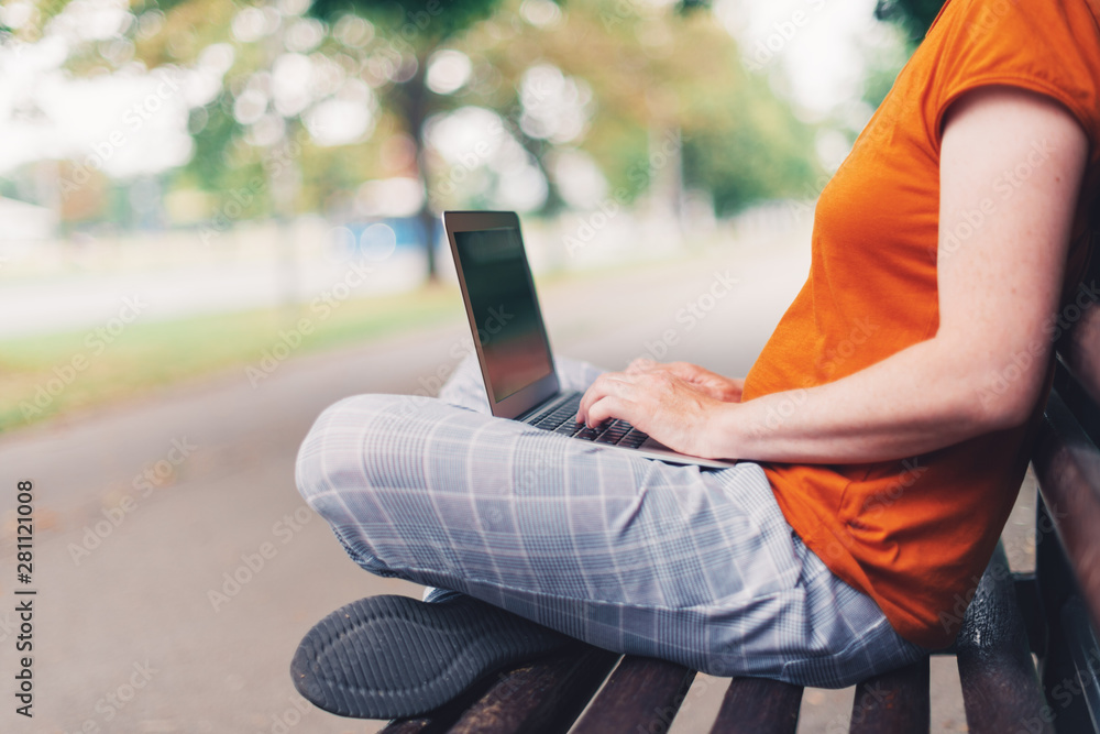 Naklejka premium Woman using laptop computer on park bench
