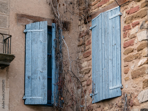 Two wooden windows, painted in blue, one close and the other semi closed, from a typical house of Gigondas, France photo