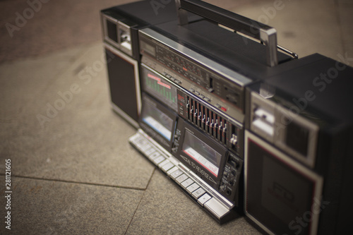 The retro boombox, an outdated portable radio with a cassette recorder from the 80s, stands on the sidewalk. Rap, hip-hop, R B music concept