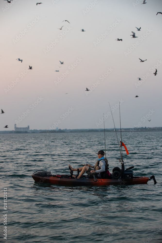 Naklejka premium Young Man Kayak Fishing at Sunrise in Canada