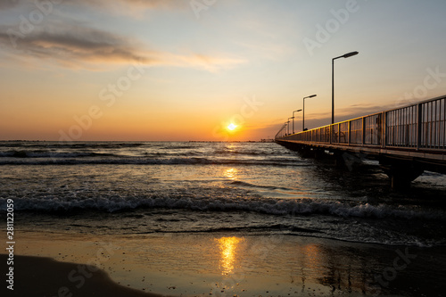 Golden sunrise and foamy waves over pontoon bridge at Black Sea