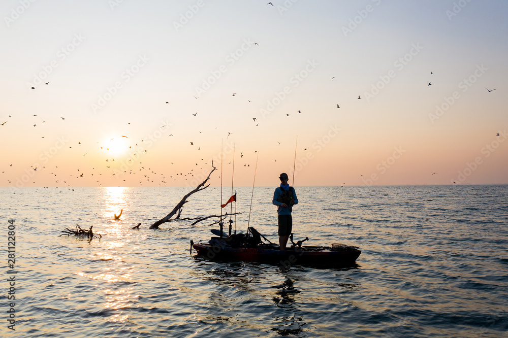 Fototapeta premium Young Man Kayak Fishing at Sunrise in Canada