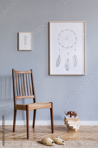 Stylish bohemian interior design of living room with retro chair, rattan slippers, books, sculpture, mock up poster frames and elegant accessories. Gray background walls. Modern home decor. Template.