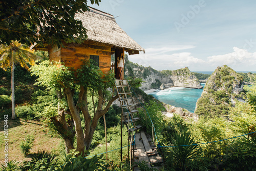 Woman standing on stairs near traditional wooden house and enjoy beautiful view on the beach photo