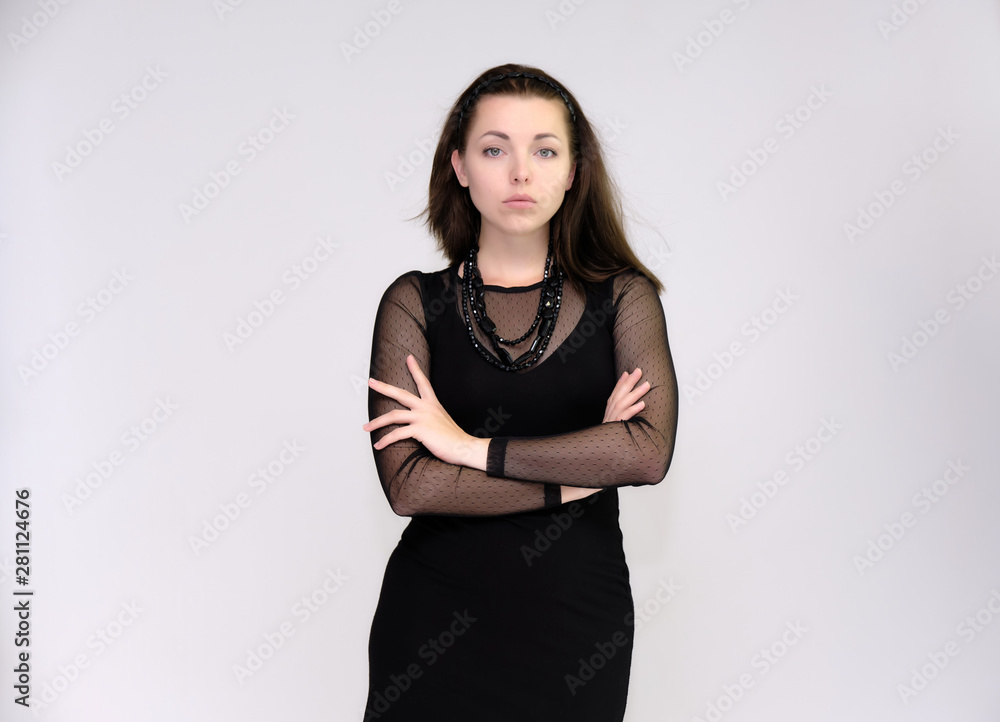 Portrait on white background of a pretty slim beautiful fashionable adult girl with beautiful brunette hair in a black dress. Standing talking demonstrating different poses and emotions Portrait on white background of a pretty slim beautiful fashionable adult girl with beautiful brunette hair in a black dress. Standing talking demonstrating different poses and emotions