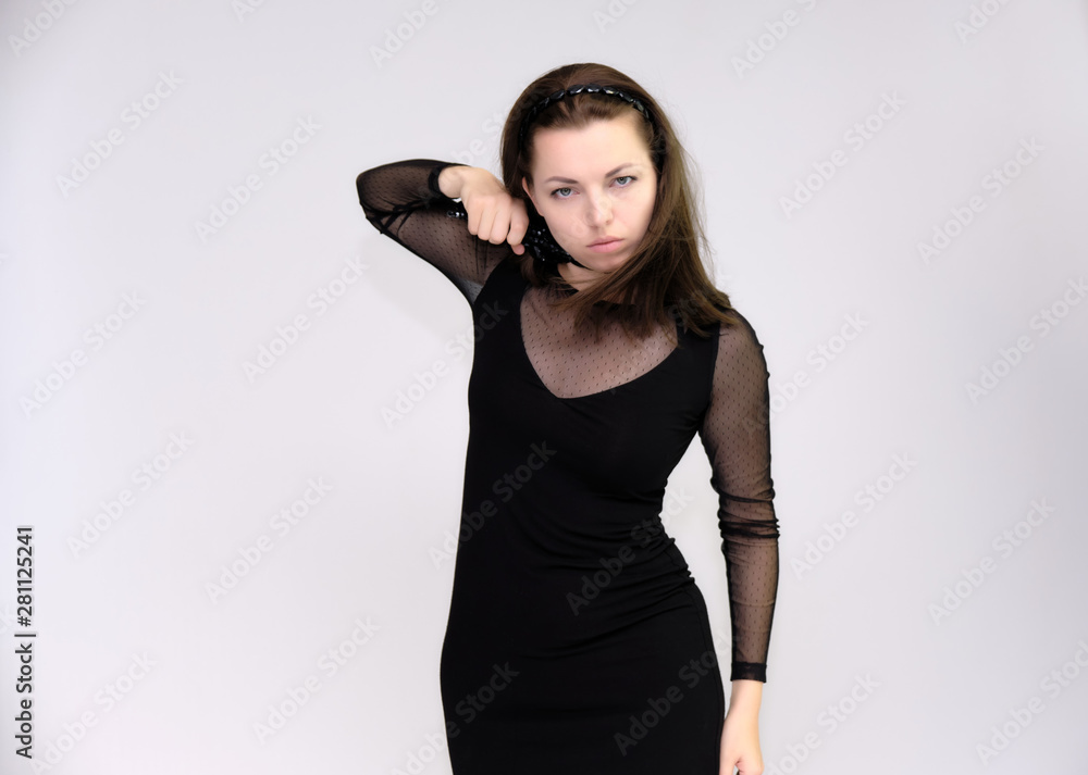 Portrait on white background of a pretty slim beautiful fashionable adult girl with beautiful brunette hair in a black dress. Standing talking demonstrating different poses and emotions Portrait on white background of a pretty slim beautiful fashionable adult girl with beautiful brunette hair in a black dress. Standing talking demonstrating different poses and emotions