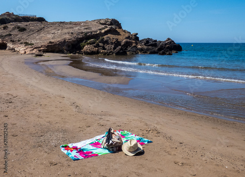  Empty beach in Costa Calida , hat, a beach bag, and a towel lie on the beach