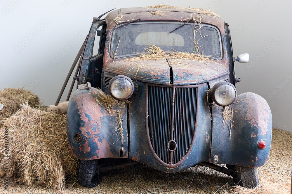Abandoned old wrecked rusty car standing in an corner of some old barn Abandoned old wrecked rusty car standing in an corner of some old barn