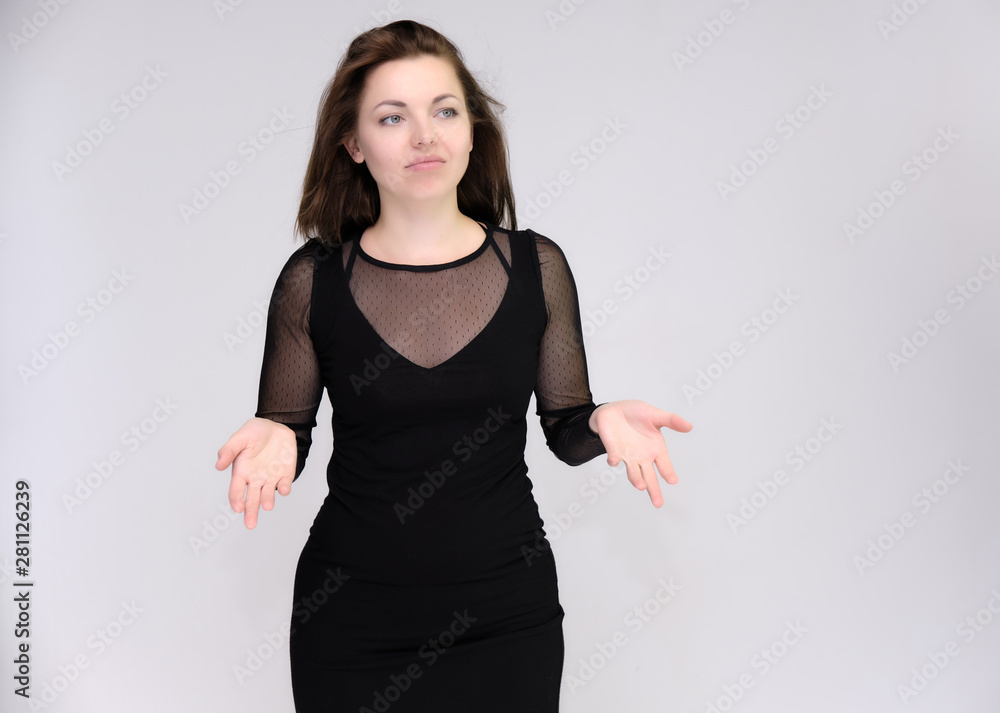 Portrait on white background of a pretty slim beautiful fashionable adult girl with beautiful brunette hair in a black dress. Standing talking demonstrating different poses and emotions Portrait on white background of a pretty slim beautiful fashionable adult girl with beautiful brunette hair in a black dress. Standing talking demonstrating different poses and emotions
