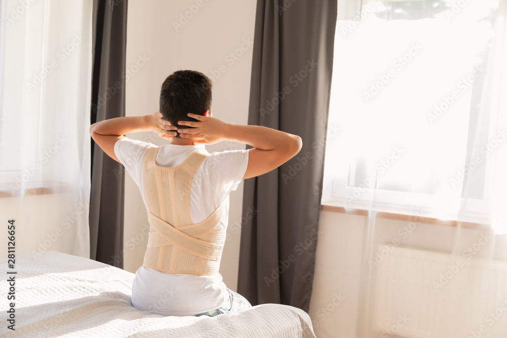 Young man wearing a back support belt. Lumbar brace, back support for back trauma or muscle back strain. Young man wearing a back support belt. Lumbar brace, back support for back trauma or muscle back strain.