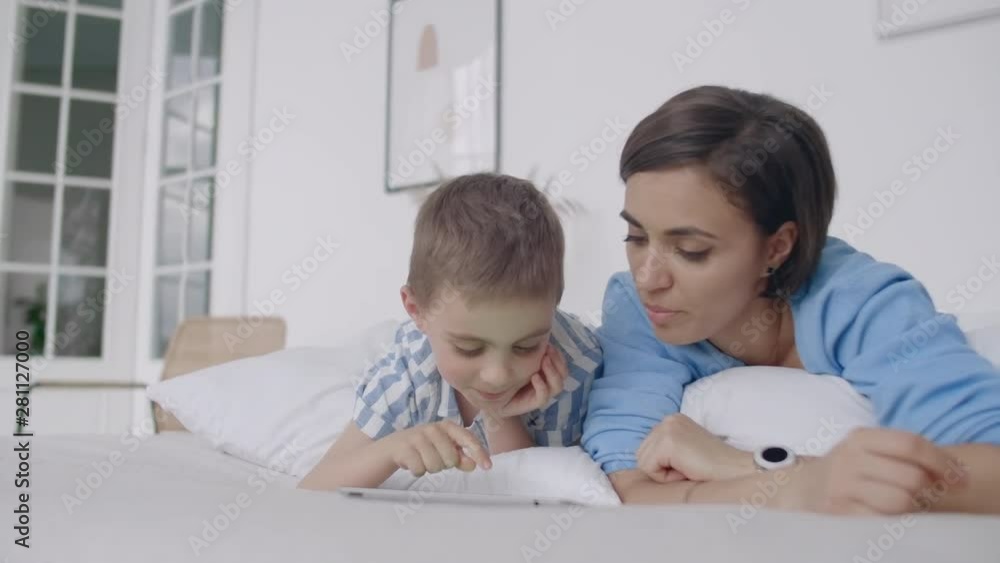 Happy family mother and child son with tablet in evening. Happy family mother and child son with tablet in evening before bed. Happy family mother and child son with tablet in evening. Happy family mother and child son with tablet in evening before bed.