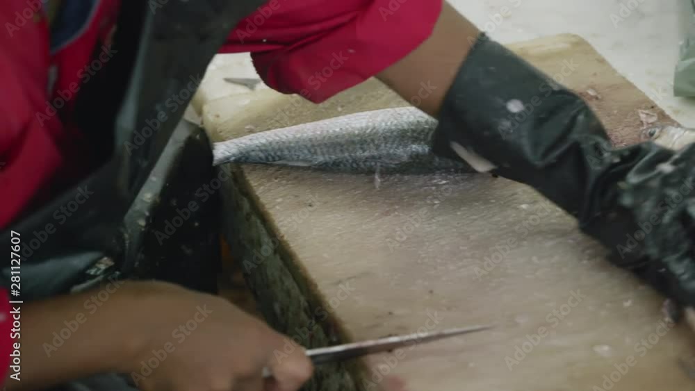 Fish monger chopping the head off a trout Fish monger chopping the head off a trout