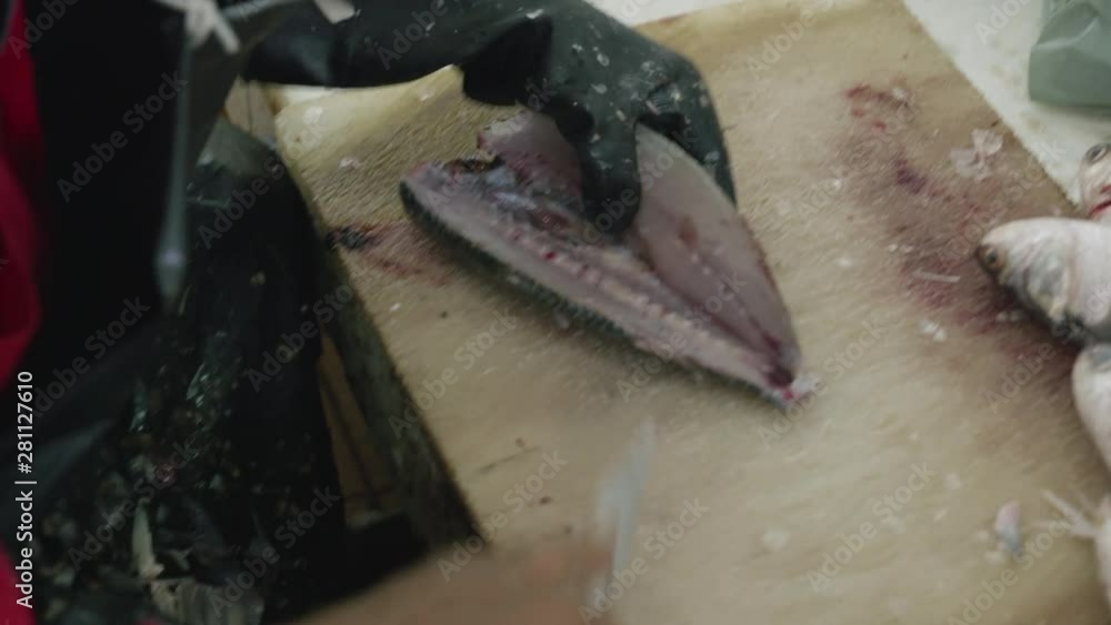 Fish monger filleting a fish. Messy offcuts covers the worker Fish monger filleting a fish. Messy offcuts covers the worker