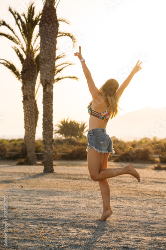 Attractive blonde woman enjoying her freedom and holiday with arms open on a paradise beach. Holiday and surfer concept.