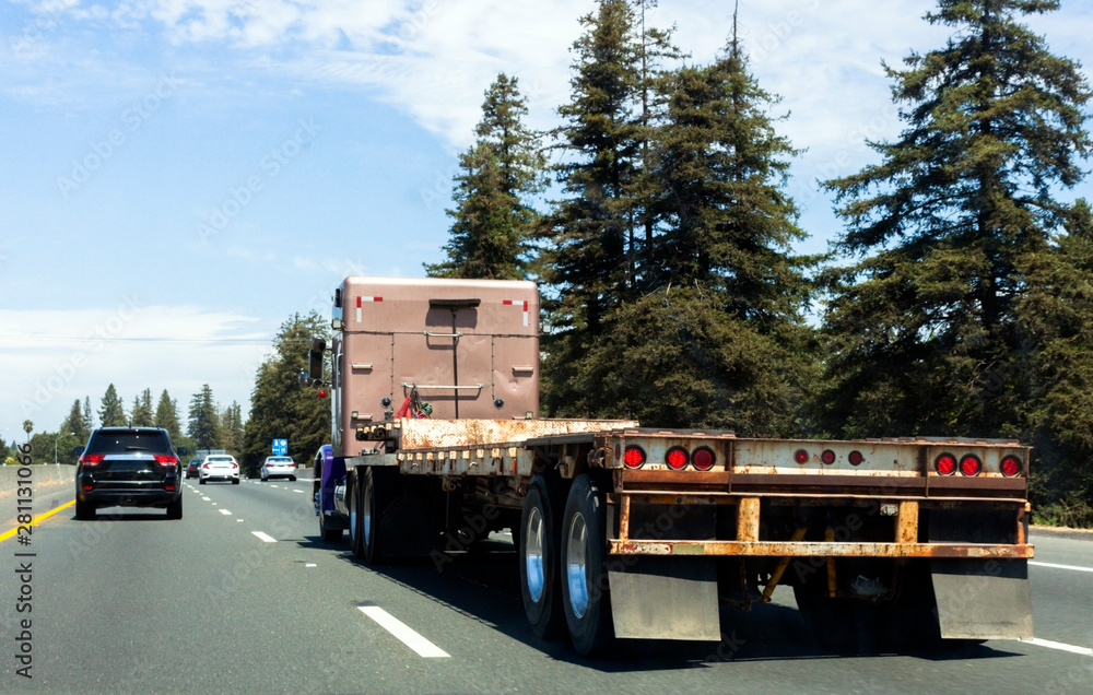 Semi truck on highway with empty flatbed trailer.