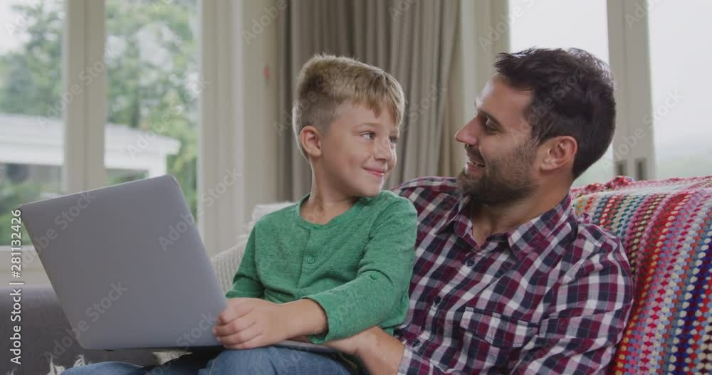 Father and son using laptop on sofa in a comfortable home 4k Father and son using laptop on sofa in a comfortable home 4k