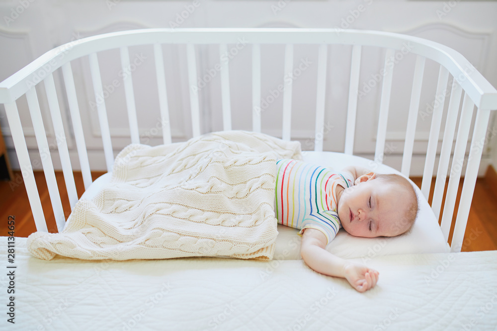 Baby sleeping in cosleeper crib attached to parents' bed Stock Photo