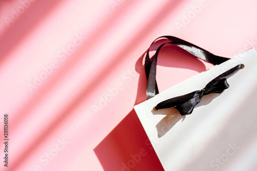 Flat lay top view White gift bag and spring flowers on a pink background. Greeting card with delicate flowers Pink floral background photo