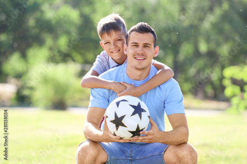Little boy and his dad with soccer ball outdoors