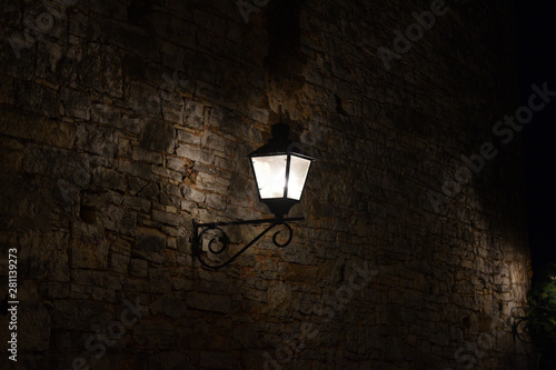 Traditional illuminated lamp on stone brick background in the nighttime.
