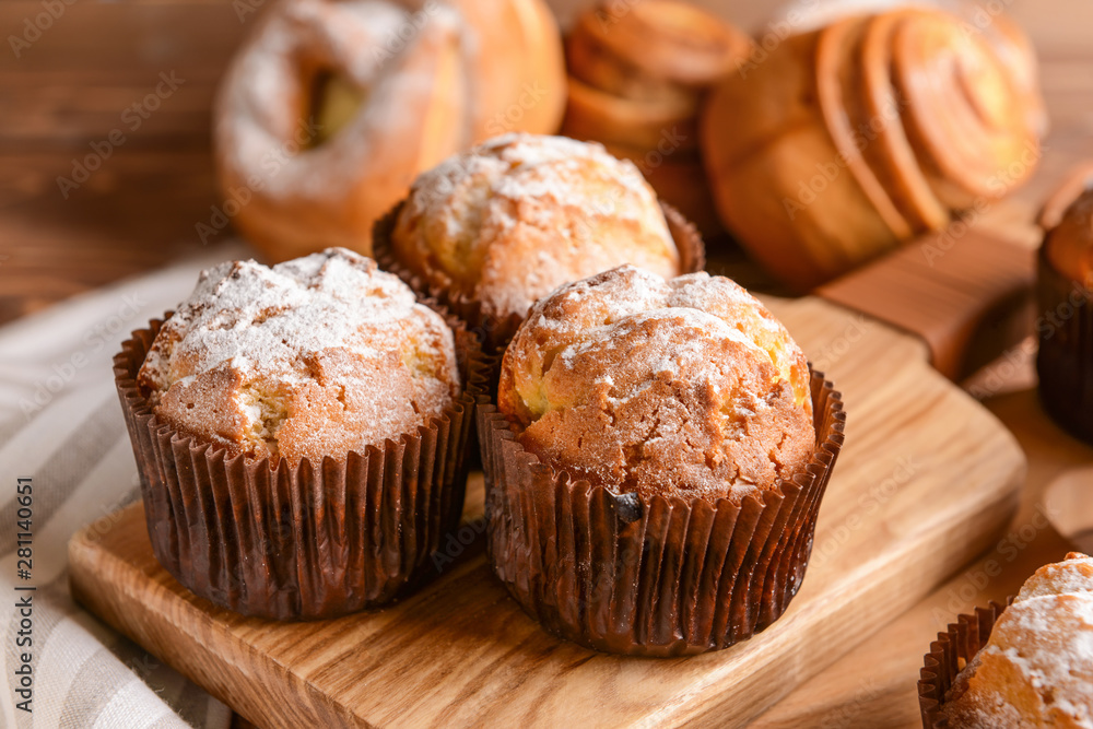 Tasty muffins on wooden board, closeup
