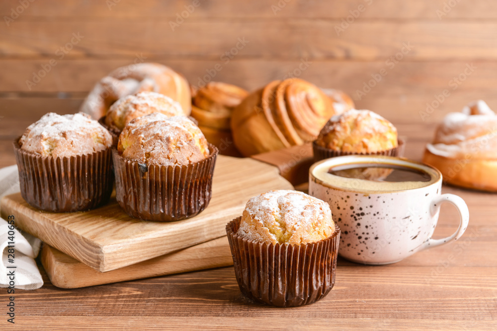 Tasty muffins with cup of coffee on wooden table