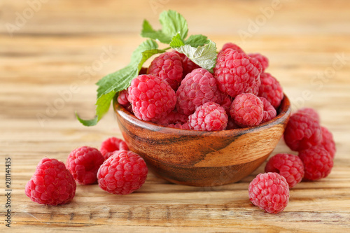 Bowl with sweet ripe raspberries on wooden table