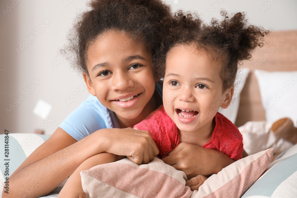 Little African-American sisters lying on bed at home Little African-American sisters lying on bed at home