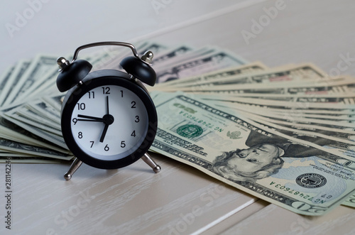 time is money. time is worth the money. time is more valuable than money. clock and dollars banknotes for business concept. copy space. soft focus