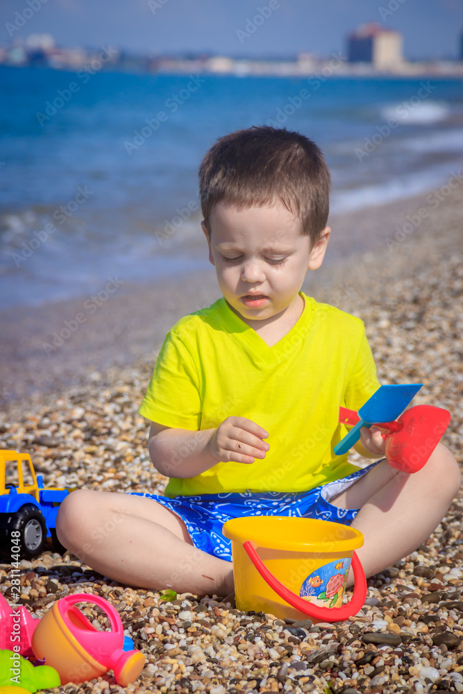 The boy plays on the beach in the toys for the sand. Children's games. Games on the beach. Galichny beach. Children's toys for sand. The baby is playing The boy plays on the beach in the toys for the sand. Children's games. Games on the beach. Galichny beach. Children's toys for sand. The baby is playing