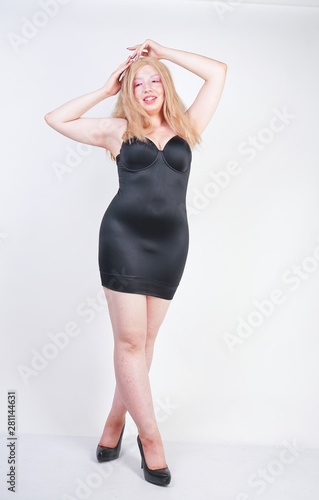 hot chubby blonde asian adult girl in sexy tight little black dress lingerie on white studio background standing alone