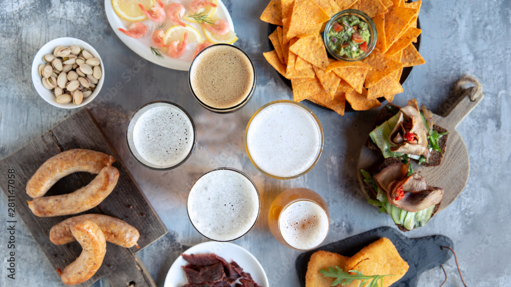 Top view of beer glasses with foam on top and delicious snacks. Sausages and sauces, chips, meat, shrimp with lemon. Concept of drinks, fun, food, celebrating, meeting, oktoberfest. Top view of beer glasses with foam on top and delicious snacks. Sausages and sauces, chips, meat, shrimp with lemon. Concept of drinks, fun, food, celebrating, meeting, oktoberfest.