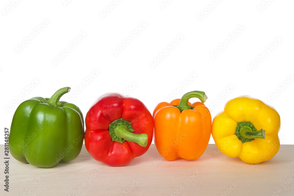 Bell Peppers on a wood table isolated on white. Green, red, orange and yellow varieties. Like the tomato, bell peppers are botanical fruits but culinary vegetables. Bell Peppers on a wood table isolated on white. Green, red, orange and yellow varieties. Like the tomato, bell peppers are botanical fruits but culinary vegetables.