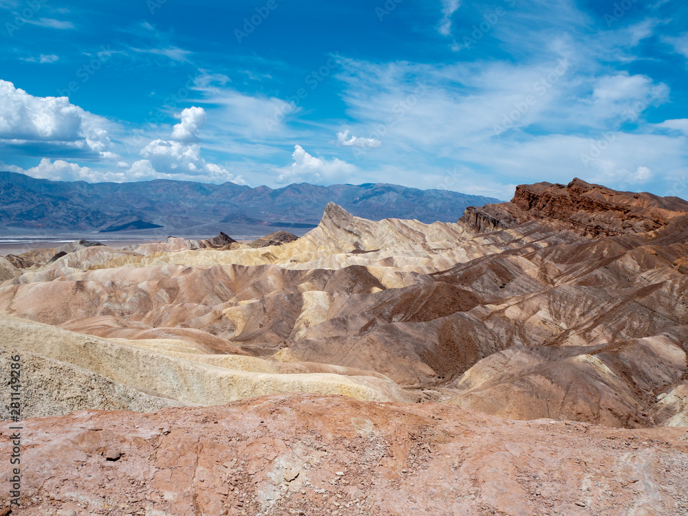 Gold, orange and brown layer hills of Zabriskie Point in the hot desert badlands of Death Valley National Park, California, USA.