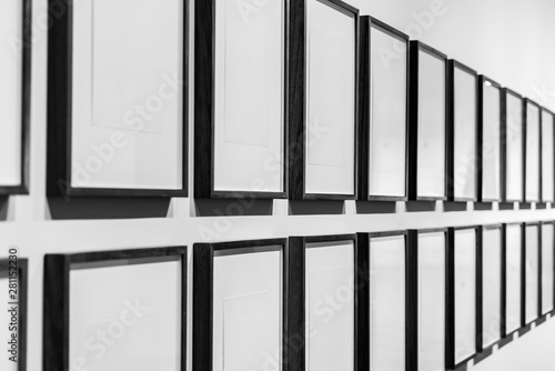 Two rows of black and white photo frames in a gallery.