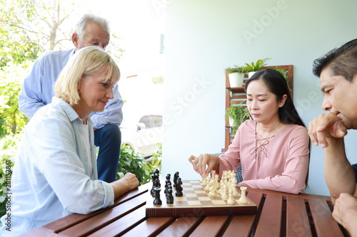 close up of a group of multiethnic senior people playing chess board with happy smiling face on holiday vacation