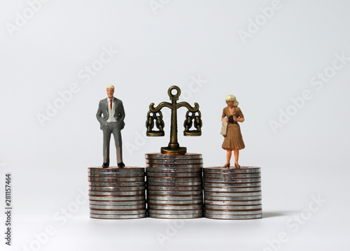 Miniature people standing on a pile of coins of the same height. photo