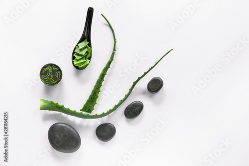 Fresh aloe vera leaves with juice and spa stones on white background