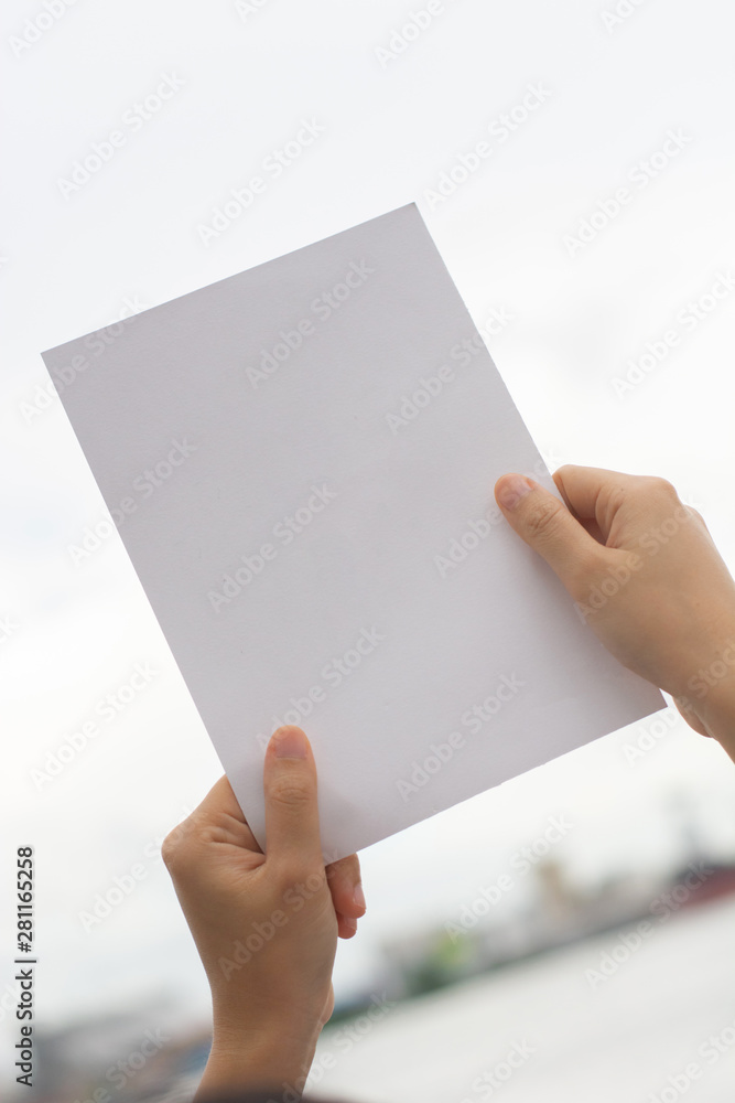 Obraz premium Kobieta trzyma puste papieru rysunku papieru papier z naturalnym tłem.